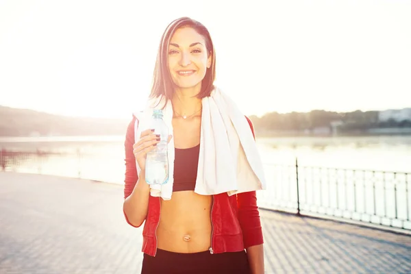 Woman holding bottle of water and a towel — Stock Photo, Image