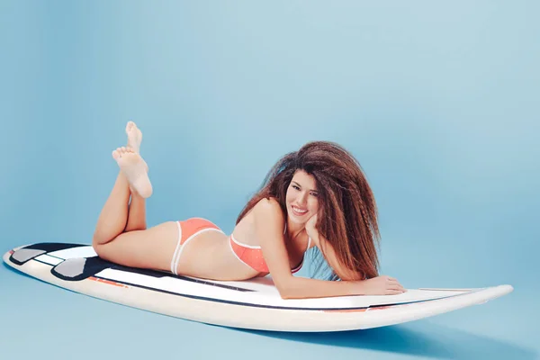 서핑 보드에 누워 웃는 소녀 — 스톡 사진