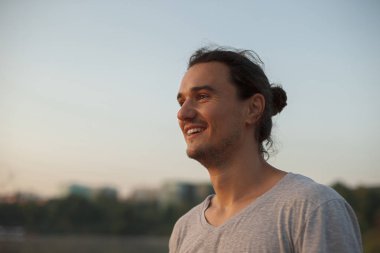 Parkta gülümseyen yakışıklı adam.