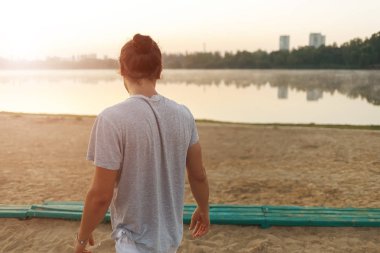 Yakışıklı adam doğarken parkta lacke üzerinde seyir.