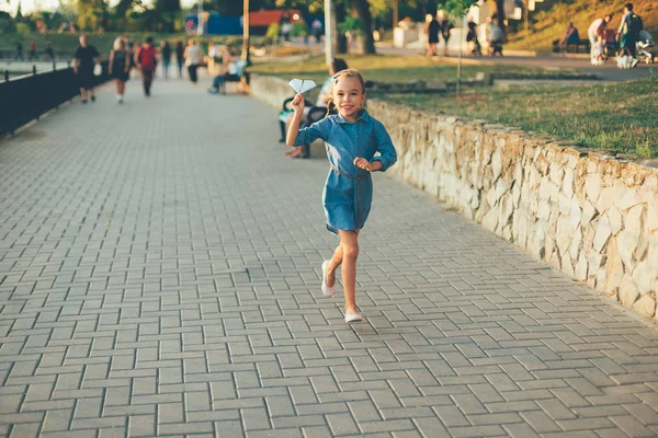 Lächelndes Mädchen läuft mit Spielzeugpapier-Flugzeug — Stockfoto