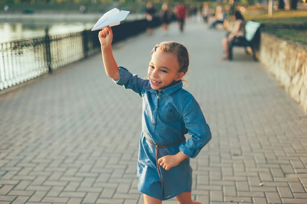 Дівчина грає, біжить з іграшковим паперовим літаком — стокове фото