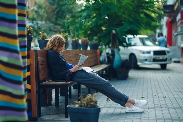 Hipster deitado no banco lendo jornal — Fotografia de Stock