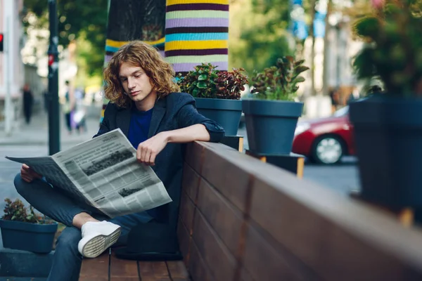 Uomo hipster dai capelli rossi seduto sulla panchina a leggere il giornale — Foto Stock