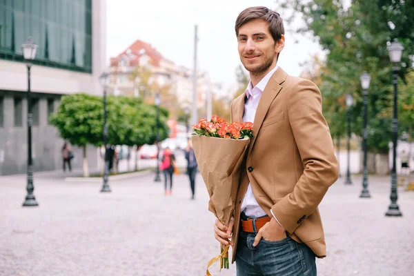 Portrait of young handsome man smiling holding a bunch of roses — Stock Photo, Image