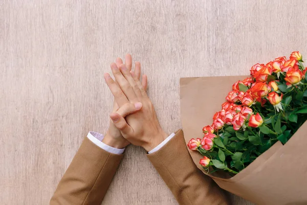 Ακριβή άνθρωπος χεριών με την παλάμη πάνω από φοίνικες και ένα μάτσο τριαντάφυλλα — Φωτογραφία Αρχείου