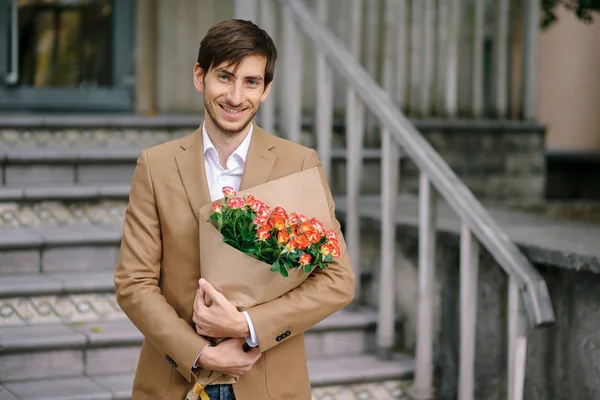 Hombre guapo sosteniendo ramo de rosas sonrisas mostrando dientes — Foto de Stock