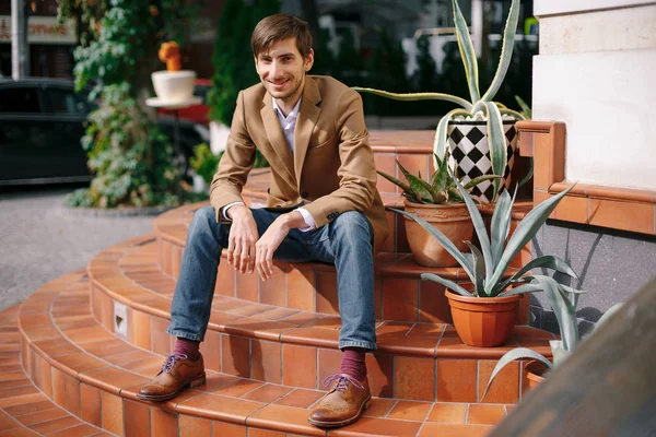 Sorridente giovane uomo elegante seduto all'aperto su vintage circolare s — Foto Stock