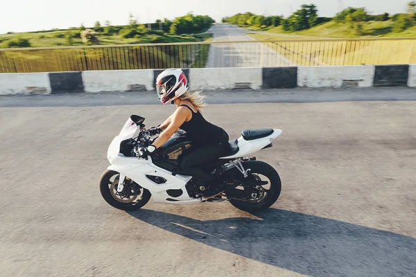 Mujer motociclista conduciendo una moto en una carretera — Foto de Stock
