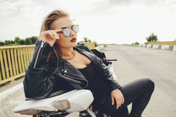 Schöne Frau posiert mit Sonnenbrille auf einem Motorrad — Stockfoto