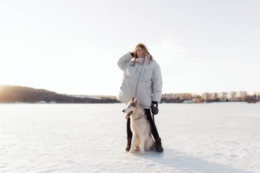 Mutlu genç kız kış parkında Sibirya köpeğiyle oynuyor.