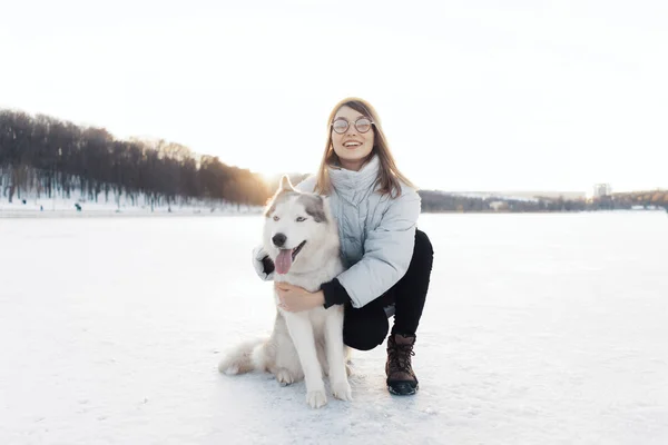 Happy young girl playing with siberian husky dog in winter park — Stock Photo, Image