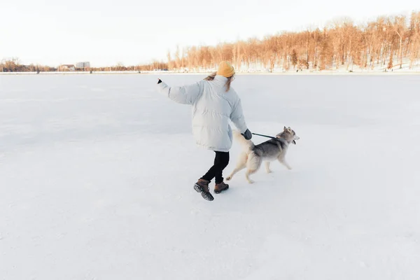 Glückliches junges Mädchen spielt mit sibirischem Husky-Hund im Winterpark — Stockfoto