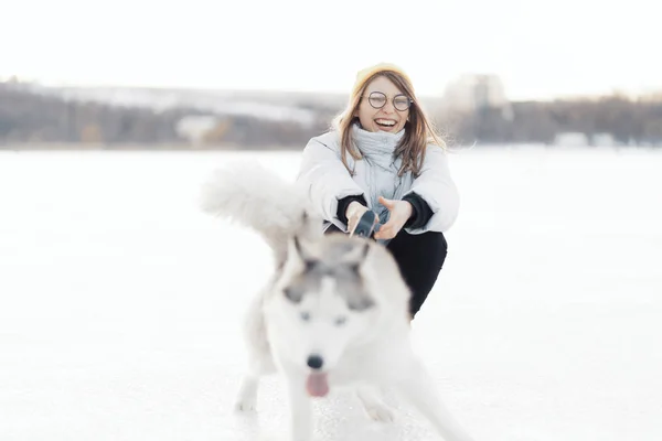 Ευτυχισμένο νεαρό κορίτσι παίζει με σιβεριανό husky σκυλί στο πάρκο το χειμώνα — Φωτογραφία Αρχείου