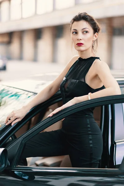 Sensuale donna pericolosa in piedi con uno sguardo felino nella porta di una macchina pronta a vincere il mondo — Foto Stock