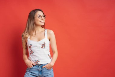 Güzel kadın model kırmızı arka plan üzerinde gülümseyen bir yüz ifadesi ile poz