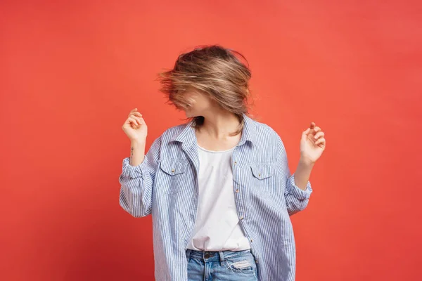 Menina casual alegre se divertindo no estúdio brincando com o cabelo no fundo vermelho . — Fotografia de Stock