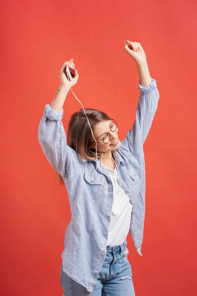 Lächelndes Mädchen in lässiger Kleidung und Kopfhörer, das bewegliche Hände tanzt. — Stockfoto