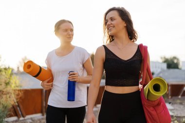 Spor giyimli iki güzel kadın spor antrenmanı, jimnastik ve yoga yapacaklar.