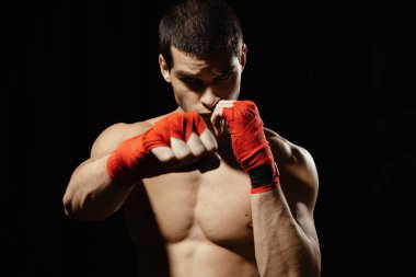 Atletik boksör siyah arka planda kararlılık ve önlem ile yumruk atıyor. Güç, saldırı ve hareket konsepti. Kafkas modelini hareket halinde sığdır