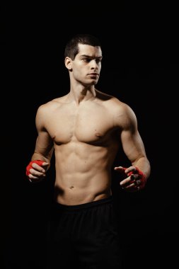 Siyah arka plana karşı boks pozisyonunda poz veren erkek boksörün portresi.