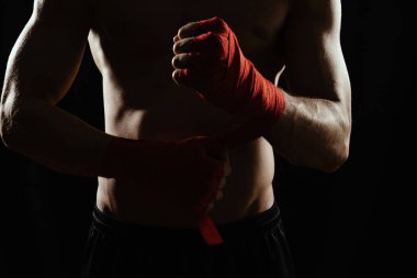 Close-up of the hands of a young boxer who winds red bandages before a match, fight or training. clipart