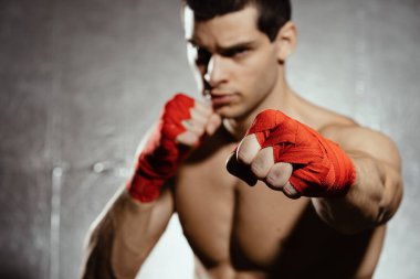Atletik boksör gümüş arka planda kararlılık ve önlem ile yumruk atıyor. Güç, saldırı ve hareket konsepti. Kafkas modelini hareket halinde sığdır