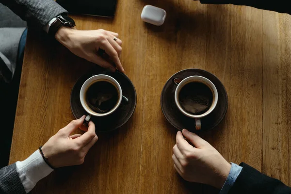 Le mani degli uomini gesticolando mentre tengono tazze di caffè — Foto Stock