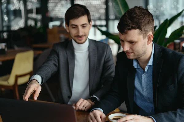 Zwei Geschäftsleute zeigen beim Gespräch auf Laptop-Bildschirm — Stockfoto