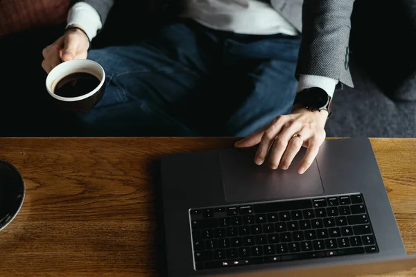 Mãos de homem de negócios trabalhando em laptop segurando xícara de café — Fotografia de Stock