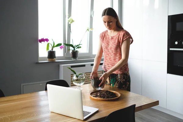 Vrouw herplanten bloem met behulp van online instructies op de laptop — Stockfoto