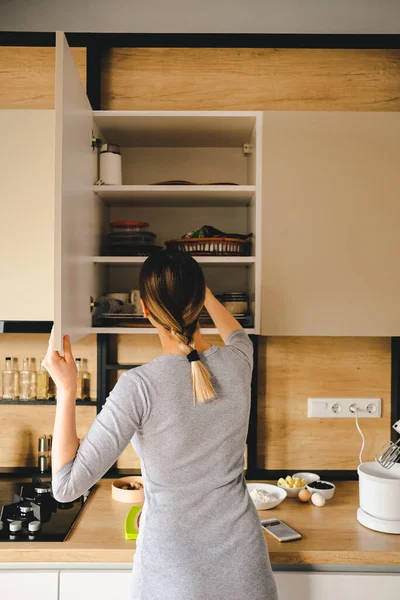 Жінка вдома бере щось з кухонного магазину — стокове фото