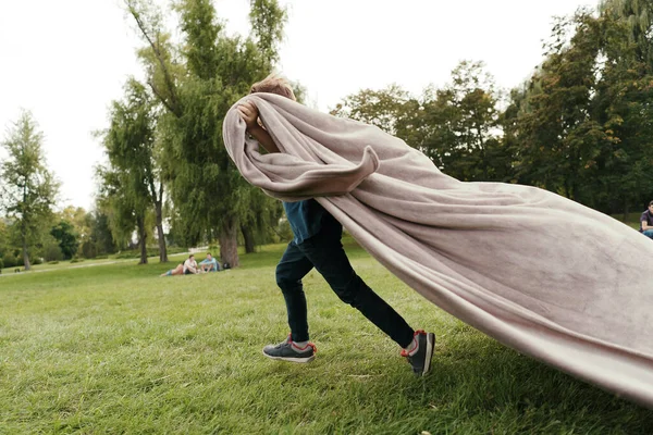 Parkta uçan battaniyeyle koşan neşeli çocuk. — Stok fotoğraf