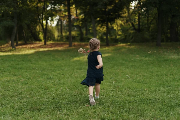 Yeşil çimenlerde koşan neşeli küçük kız — Stok fotoğraf
