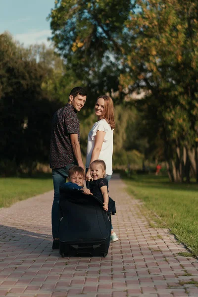 Happy couple carry their kids in a briefcase while playing — Stock Photo, Image