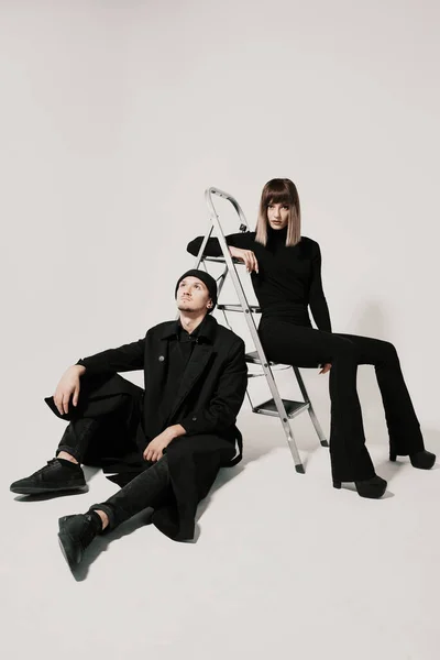 Hombre y mujer de moda sentados en una escalera — Foto de Stock
