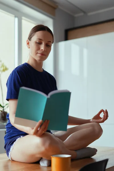 Чтение в позе йоги на стол остаться дома деятельности — стоковое фото