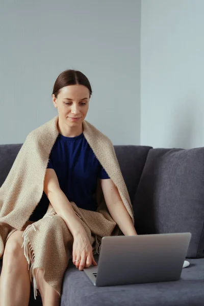 Jonge vrouw knuffelen in een warme deken met een laptop — Stockfoto