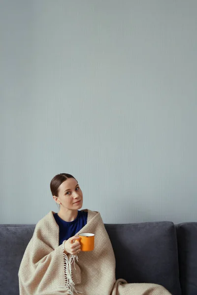 Positieve vrouw genieten van een kopje thee verpakt in een deken — Stockfoto