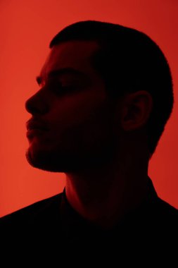 Genç, kendine güvenen yakışıklı bir iş adamının silueti kırmızı ışıkta siyah gömlek giyiyor.