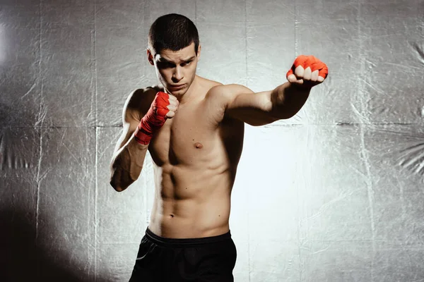 Atletik boksör gümüş kground üzerinde azim ve önlem ile yumruk atıyor — Stok fotoğraf