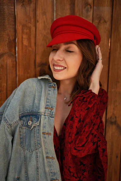 Portret modieuze vrouw met rode pet op houten achtergrond — Stockfoto