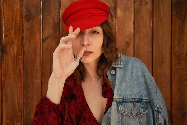 Ritratto donna alla moda in berretto rosso su sfondo legno — Foto Stock