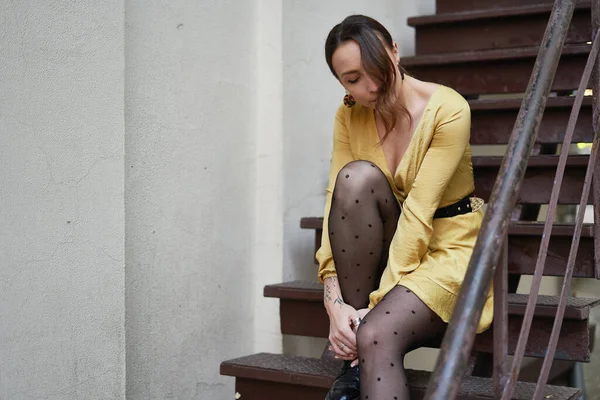 一个穿着黄色衣服的现代年轻女子站在楼梯上 — 图库照片