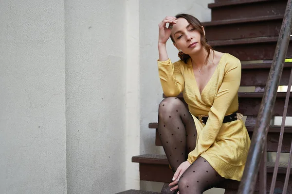 Eine moderne junge Frau im gelben Kleid posiert auf der Treppe — Stockfoto