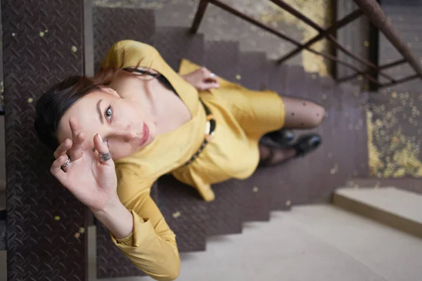 Uma jovem mulher moderna em vestido amarelo posando em escadas — Fotografia de Stock