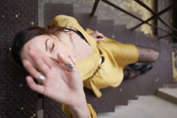 Сучасна молода жінка в жовтому платті позує на сходах — стокове фото