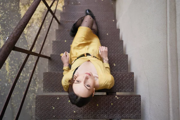 Uma jovem mulher moderna em vestido amarelo posando em escadas — Fotografia de Stock