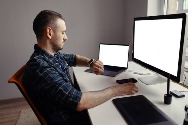 Evinde beyaz ekranlı bilgisayarda çalışan bir adam