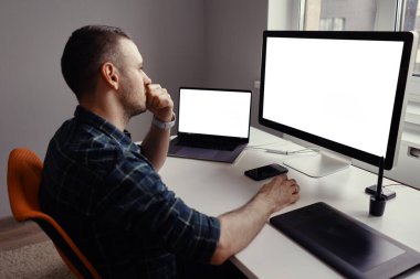 Evinde beyaz ekranlı bilgisayarda çalışan bir adam